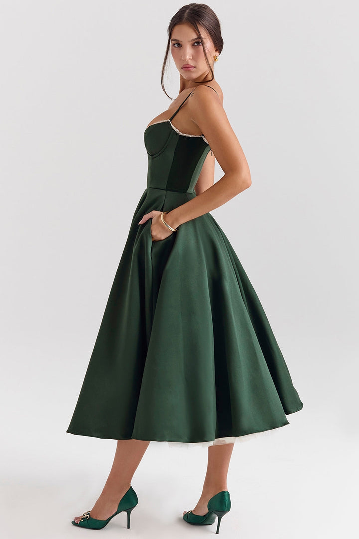 Frau in elegantem, grünem Abendkleid mit Spaghettiträgern und weitem Rock, kombiniert mit passenden grünen High Heels, vor weißem Hintergrund.