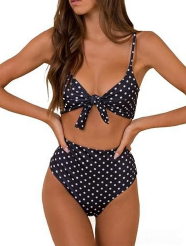 Frau in gepunktetem Bikini mit hoher Taille, schwarzer Hintergrund, modisches Sommeroutfit, Strandmode, trendiger Badeanzug, Damenbekleidung.