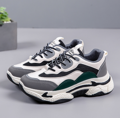 Graue und weiße Sneaker mit grünen Akzenten auf grauem Hintergrund, modisches Design, bequeme Sportschuhe, ideal für Freizeit und Sport.