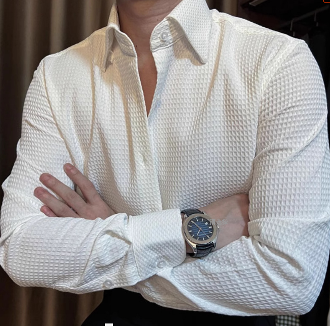 Mann in weißem Hemd mit gekreuzten Armen, trägt eine elegante Armbanduhr. Businessmode, Herrenbekleidung, stilvoller Look.