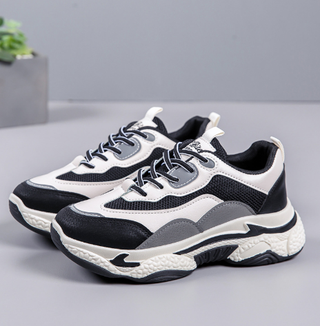 Schwarz-weiße Chunky Sneaker mit dicker Sohle und Schnürsenkeln auf grauem Hintergrund. Modische Sportschuhe für Damen und Herren.
