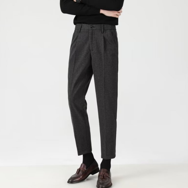Elegante graue Herrenhose aus Wolle, kombiniert mit braunen Lederschuhen und schwarzem Pullover. Stilvolle Business-Mode für Herren.