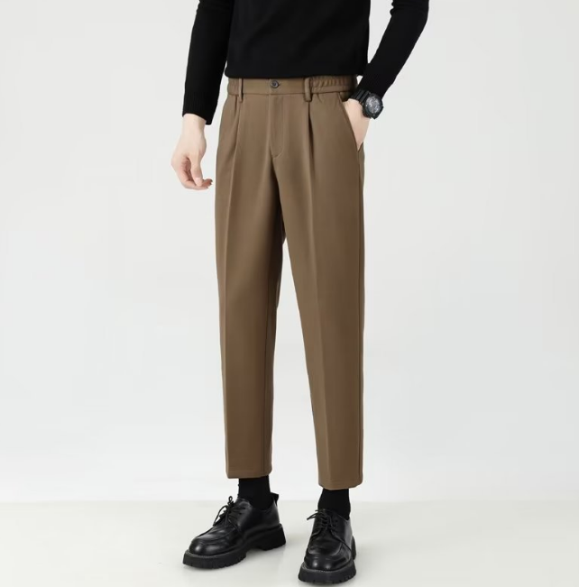 Mann in schwarzem Pullover und brauner Anzughose, schwarze Schuhe, moderne Herrenmode, stilvoll, elegant, Business-Look, minimalistisch.