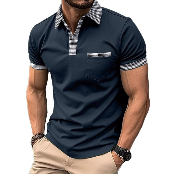 Mann in dunkelblauem Polohemd mit kariertem Kragen und Ärmeln, beige Hose, Armbanduhr. Modische Herrenbekleidung, Freizeitlook.