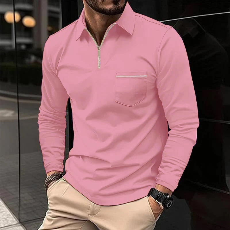 Mann in rosa Langarmshirt mit Reißverschluss und Brusttasche, beige Hose, Armbanduhr, städtische Kulisse. Herrenmode, Freizeitlook.