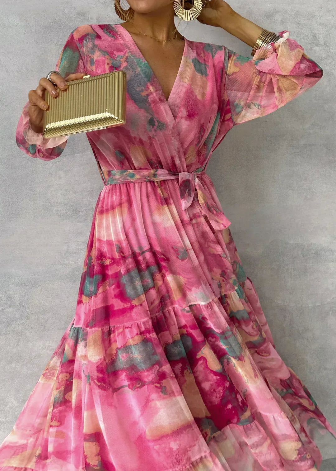 Frau in elegantem, langem, pinkem Kleid mit abstraktem Muster, hält goldene Clutch. Modetrend, Abendmode, stilvolles Outfit.