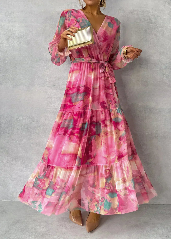 Frau in langem, geblümtem Kleid in Rosa mit V-Ausschnitt, hält goldene Clutch. Elegantes Abendoutfit, modisch, stilvoll, feminin.