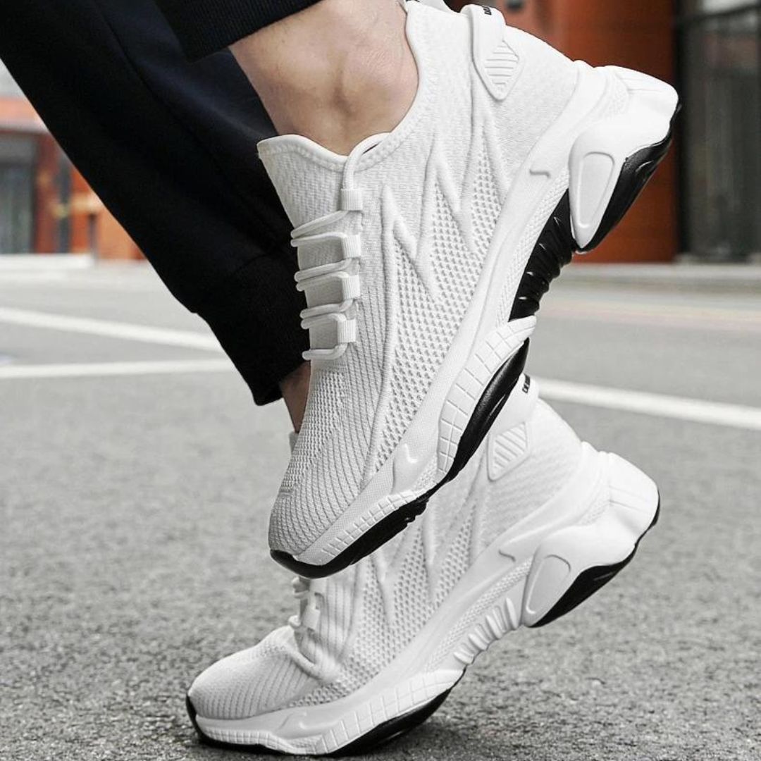 Weiße Sportschuhe mit schwarzer Sohle auf Asphalt, modernes Design, atmungsaktives Material, ideal für Laufen und Fitness, urbaner Hintergrund.
