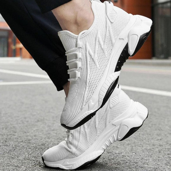 Weiße Sportschuhe mit schwarzer Sohle auf Asphalt, modernes Design, atmungsaktives Material, ideal für Laufen und Fitness, urbaner Hintergrund.