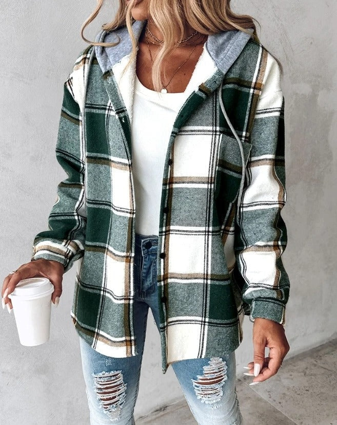 Frau in kariertem Flanellhemd mit Kapuze, weißem Top und zerrissenen Jeans hält Kaffeebecher. Modetrend Herbst, lässiger Streetstyle.