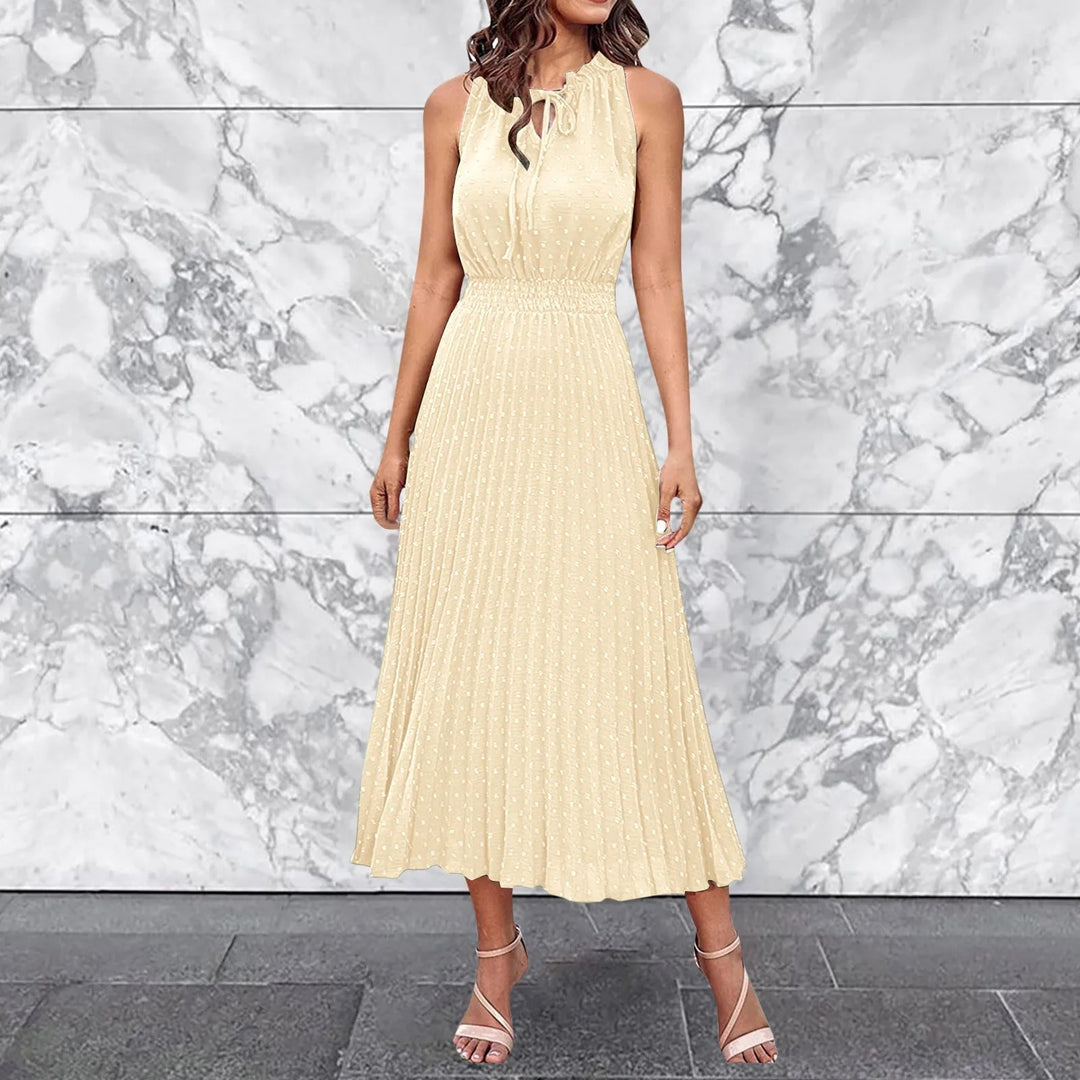 Frau in elegantem, ärmellosem, cremefarbenem Kleid vor Marmorrückwand, modisches Outfit, Sommermode, stilvolle Sandalen.