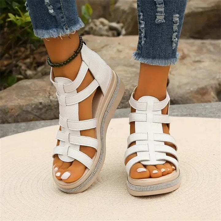 Weiße Sandalen mit Plateauabsatz, getragen von einer Person in zerrissenen Jeans. Modische Sommerschuhe, ideal für lässige Outfits.