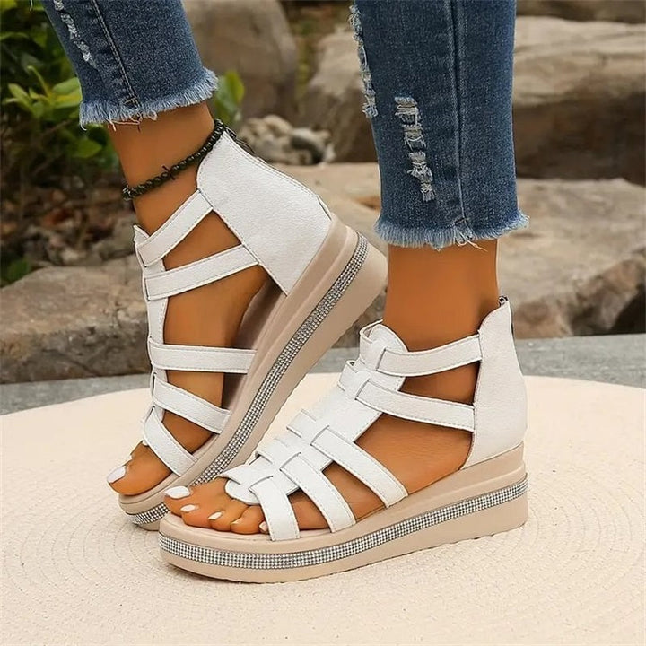 Weiße Sandalen mit Keilabsatz und Riemchen-Design, getragen von einer Person in zerrissenen Jeans. Perfekt für Sommermode und Freizeitoutfits.