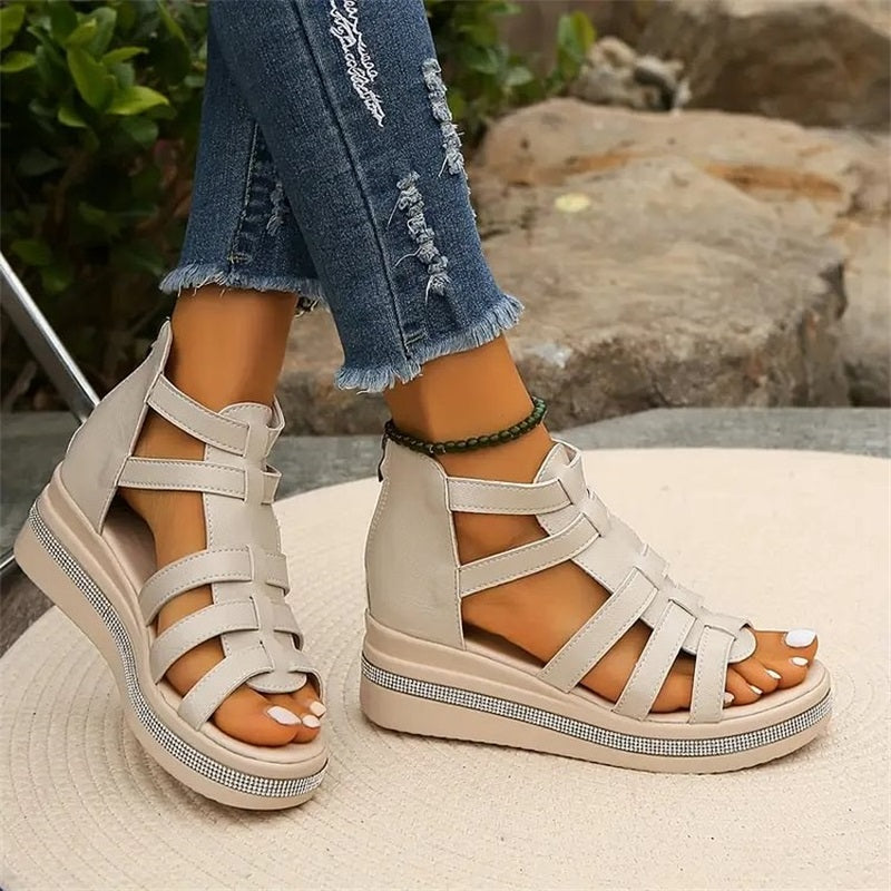 Beige Sandalen mit Keilabsatz und Riemchen, getragen zu zerrissenen Jeans. Modische Sommerschuhe für Damen, ideal für Freizeit und Strand.