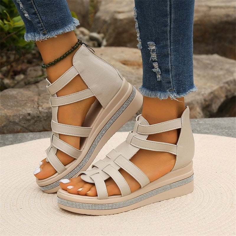 Beige Sandalen mit Keilabsatz und Riemchen, getragen von Person in zerrissenen Jeans. Modische Sommerschuhe, ideal für Freizeit und Outdoor.