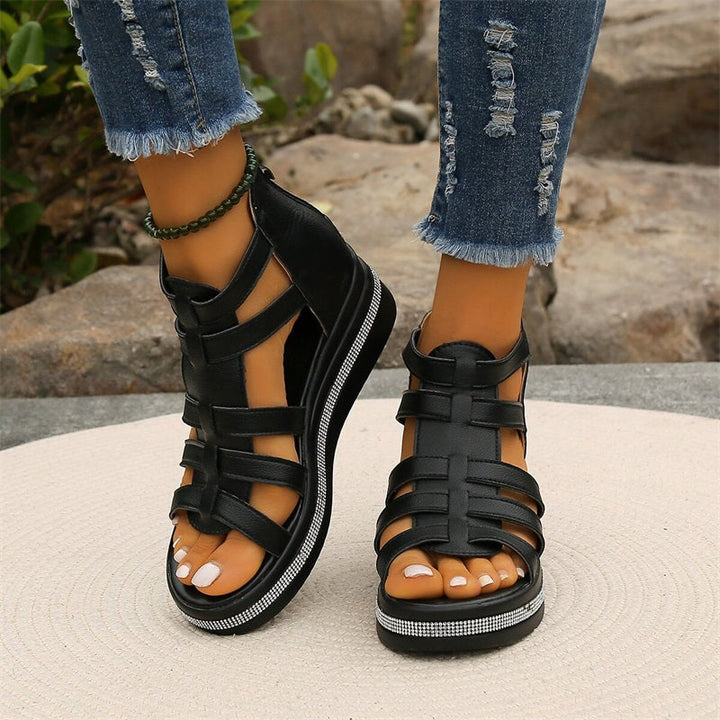 Schwarze Sandalen mit Riemchen und Glitzerdetails, getragen zu zerrissenen Jeans. Modische Damen-Sommerschuhe, ideal für Freizeit und Strand.