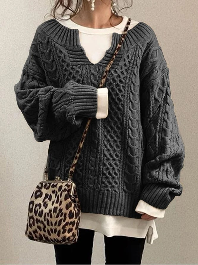 Dunkelgrauer Strickpullover mit Zopfmuster, kombiniert mit weißem Shirt und Leopardenmuster-Tasche. Modischer Herbst-Look für Damen.