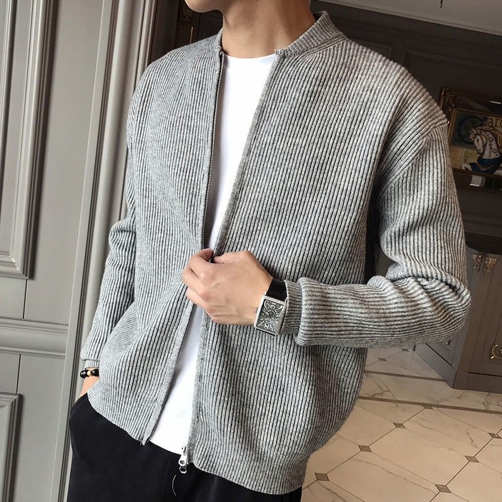 Grauer Strick-Cardigan für Herren, offen getragen über weißem T-Shirt, kombiniert mit schwarzer Hose. Eleganter, lässiger Look für Herbstmode.