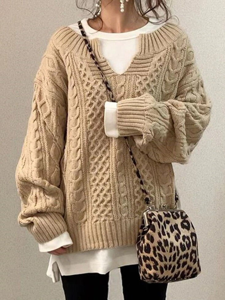 Frau in beigem Strickpullover mit Zopfmuster, weißem Shirt und Leopardenmuster-Tasche. Modetrend Herbst/Winter, lässiger Stil.
