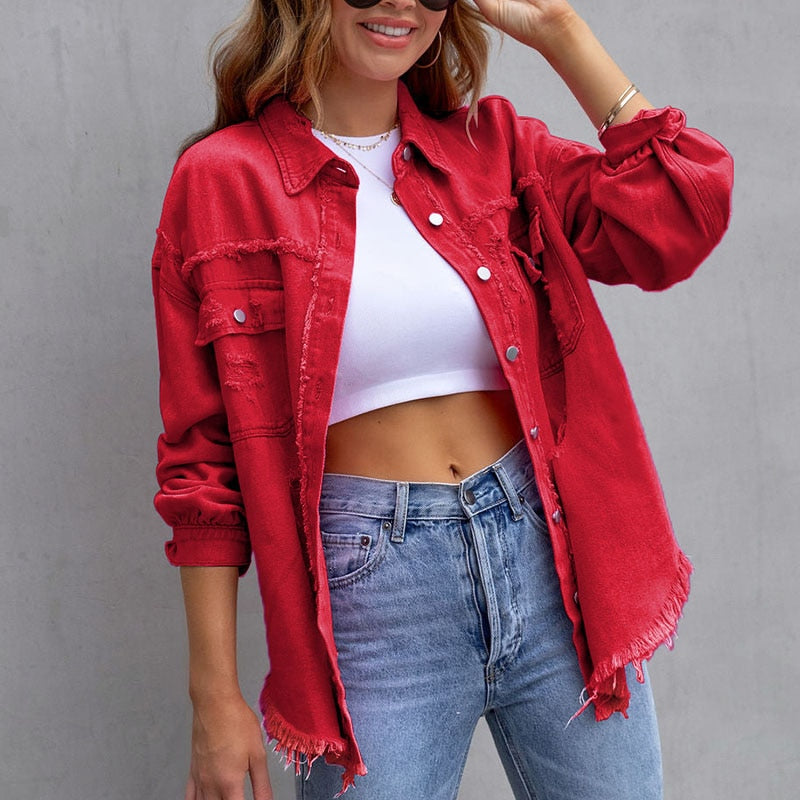 Frau in roter Jeansjacke, weißem Crop-Top und blauer Jeans vor grauem Hintergrund. Modetrend, lässiger Stil, Damenmode, Streetwear.