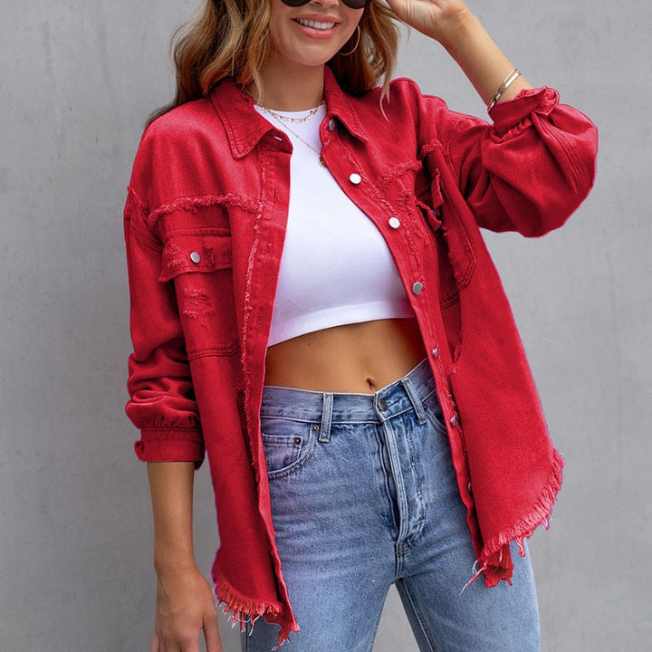 Frau in roter Jeansjacke, weißem Crop-Top und blauer Jeans vor grauem Hintergrund. Modetrend, lässiger Stil, Damenmode, Streetwear.