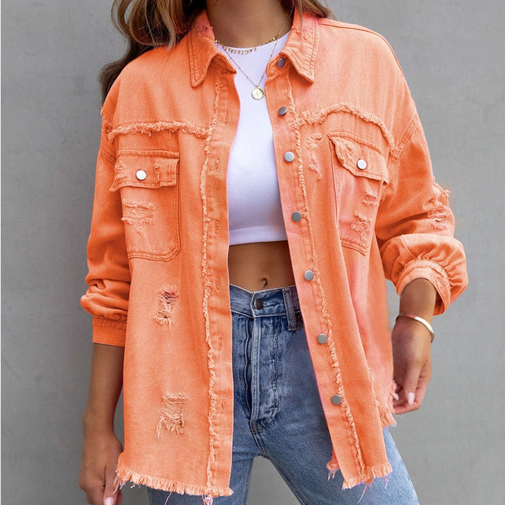 Frau in zerrissener orangefarbener Jeansjacke, weißem Top und blauen Jeans vor grauem Hintergrund. Modetrend, lässiger Stil, Damenmode.