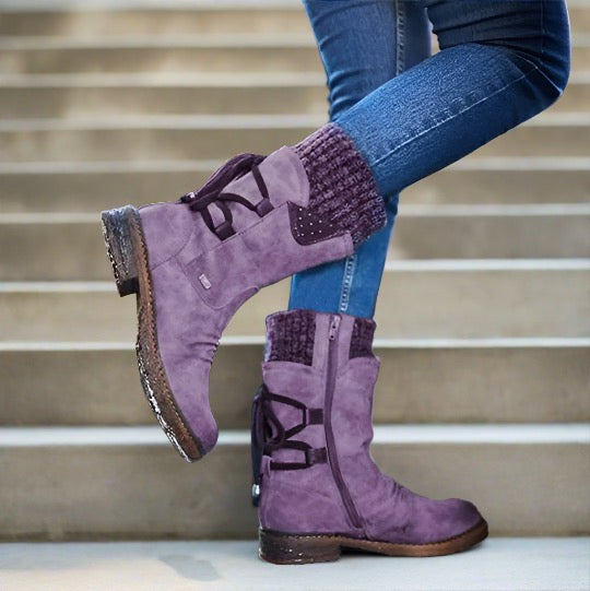 Lila Damenstiefel aus Wildleder mit Strickbündchen, seitlichem Reißverschluss und Schnürdetails, getragen auf Treppe. Modische Herbst-Winter-Schuhe.