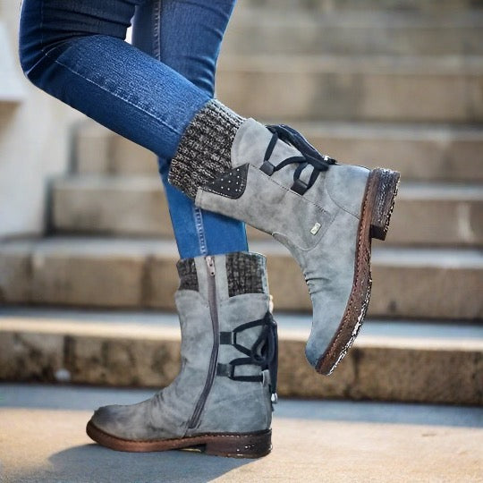 Graue Damenstiefel mit Schnürung und Strickbündchen, getragen mit blauen Jeans auf Treppe. Modische Herbst-Winter-Schuhe, bequem und stilvoll.