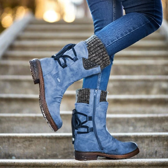Blaue Damenstiefel aus Leder mit Schnürung und Strickbündchen, getragen auf einer Treppe. Modische Herbst- und Winterstiefel für Damen.