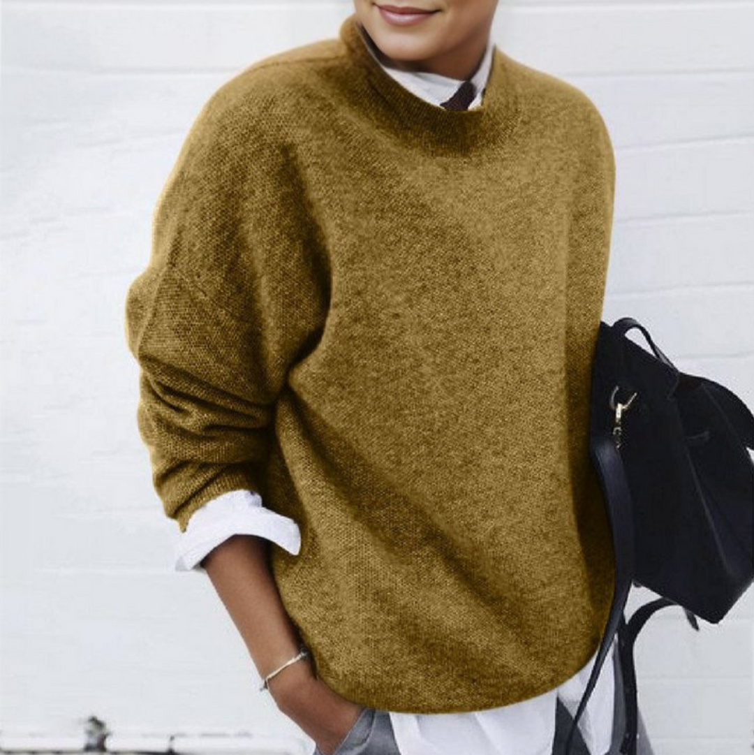 Frau in braunem Pullover und weißem Hemd, hält schwarze Tasche. Modischer Herbstlook, lässig-elegant, ideal für kühle Tage.