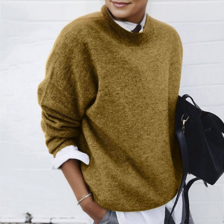 Frau in braunem Pullover und weißem Hemd, hält schwarze Tasche. Modischer Herbstlook, lässig-elegant, ideal für kühle Tage.