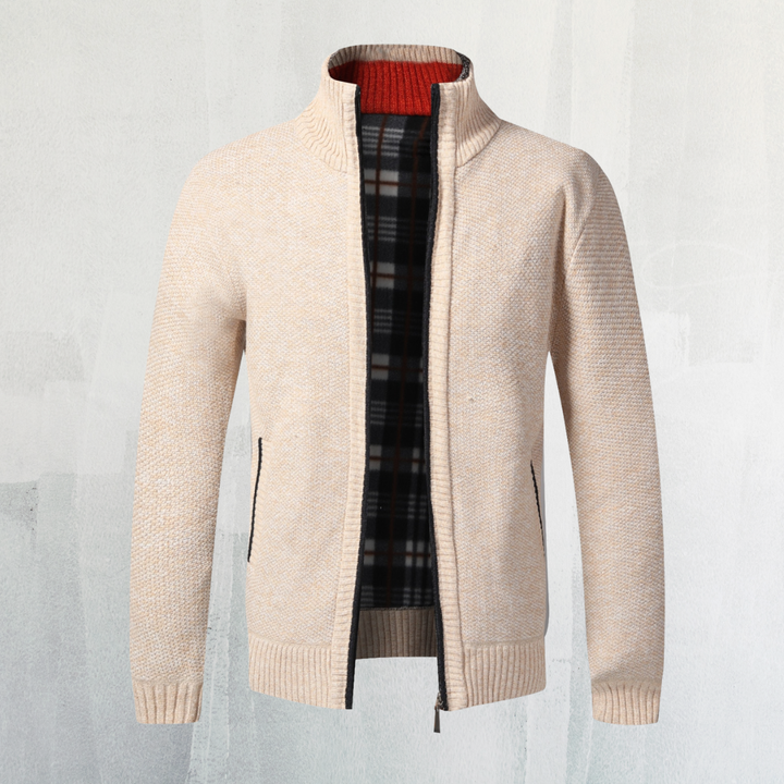Beige Strickjacke mit Reißverschluss, kariertem Innenfutter und Stehkragen vor hellem Hintergrund. Modische Herrenbekleidung, warm und stilvoll.