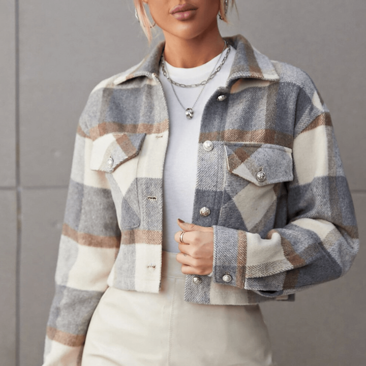Frau trägt karierte Wolljacke in Grau und Beige, kombiniert mit weißem T-Shirt. Modetrend Herbst, stilvolle Damenbekleidung, lässiger Look.