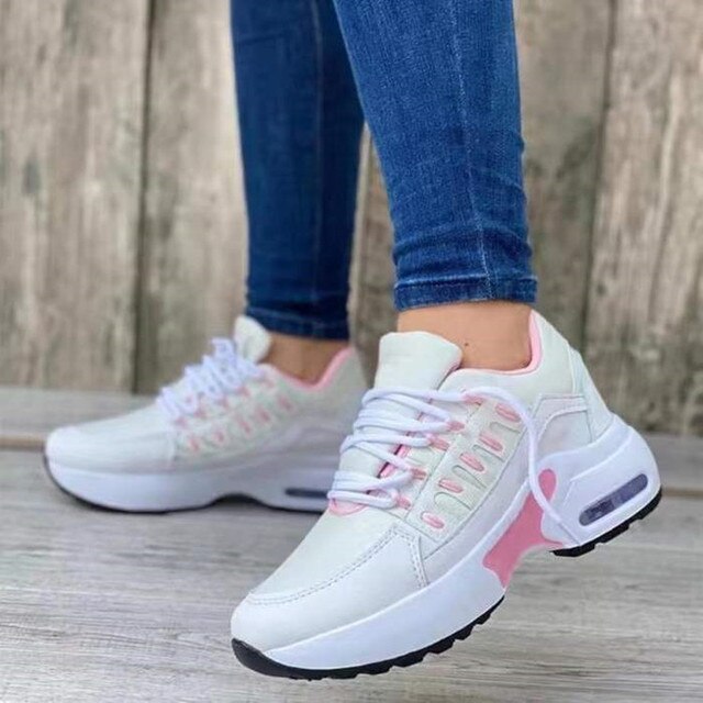 Damen-Sneaker in Weiß und Rosa, getragen mit blauen Jeans. Modische Sportschuhe, ideal für Freizeit und Sport. Bequeme Turnschuhe für Damen.