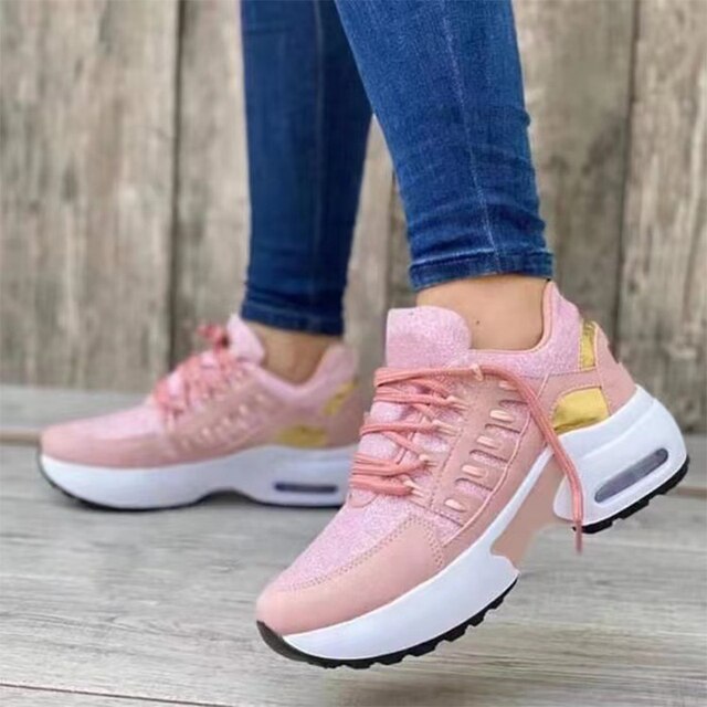 Damen Sneaker in Rosa mit goldenen Akzenten, dicker weißer Sohle und Luftpolster, getragen mit blauen Jeans. Modische Sportschuhe für Frauen.