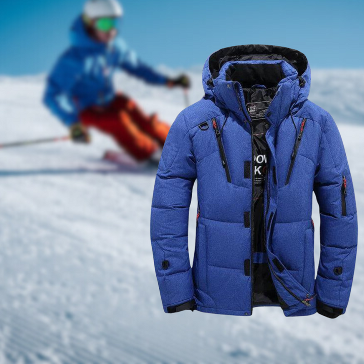 Blaue Skijacke mit Kapuze und Reißverschlusstaschen im Vordergrund, Skifahrer im Hintergrund auf schneebedecktem Hang. Wintermode, Outdoor-Bekleidung.