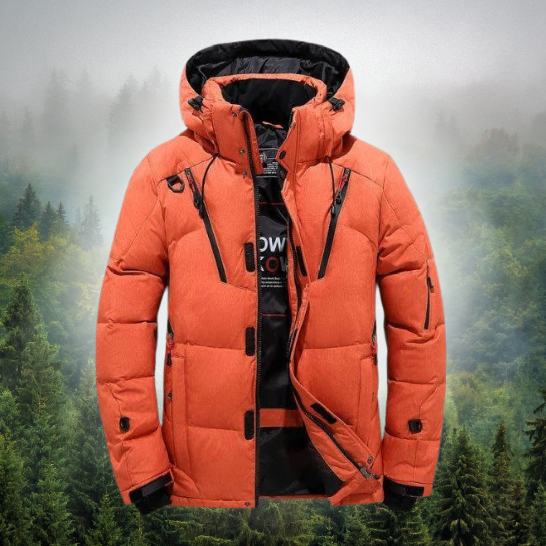 Orangefarbene Winterjacke mit Kapuze vor nebligem Waldhintergrund. Outdoor-Bekleidung, warm, wasserdicht, ideal für kaltes Wetter und Wandern.