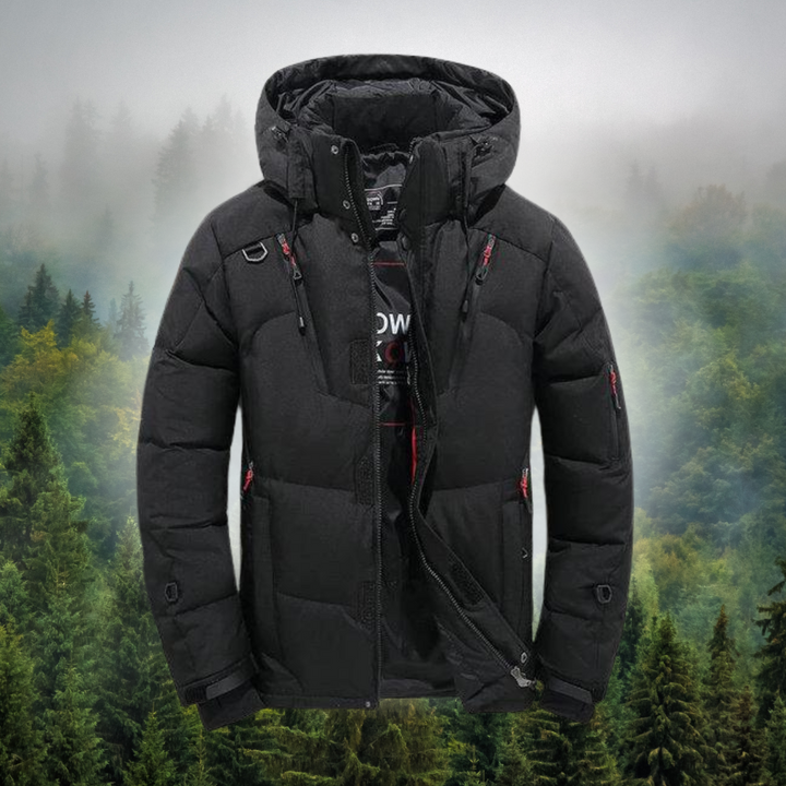 Schwarze Winterjacke mit Kapuze vor nebligem Waldhintergrund. Outdoor-Bekleidung, warm, wasserdicht, ideal für kaltes Wetter und Wandern.