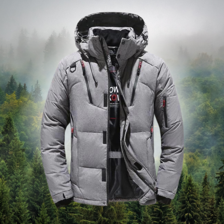 Graue Winterjacke mit Kapuze vor nebligem Waldhintergrund. Outdoor-Bekleidung, warm, wasserdicht, ideal für kaltes Wetter und Wandern.