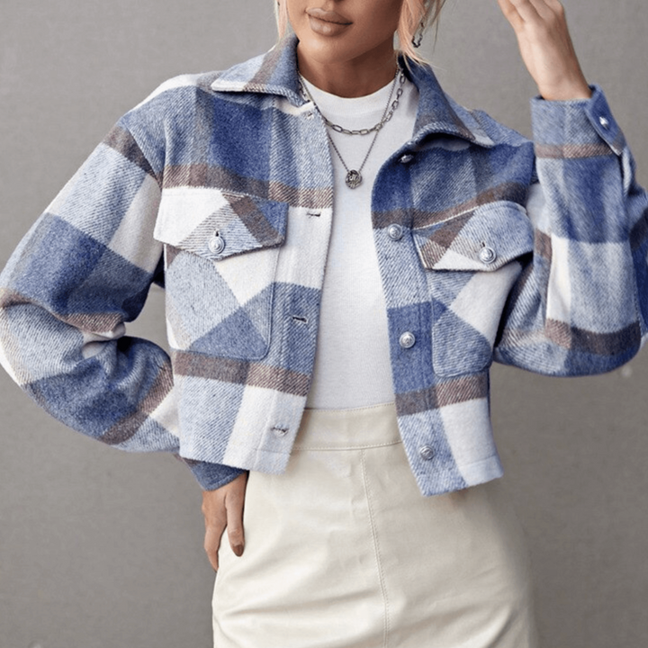 Frau trägt karierte Jacke in Blau und Weiß, kombiniert mit weißem Oberteil und beiger Hose. Modetrend, Herbstmode, Damenbekleidung.