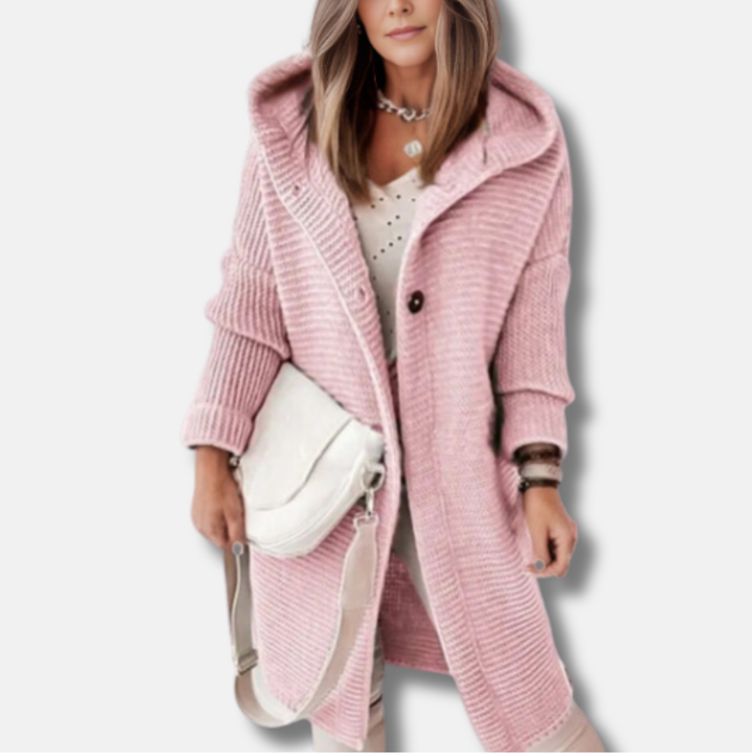 Frau in rosa Strickmantel mit Kapuze, weißem Oberteil und weißer Umhängetasche. Modetrend Herbst, Damenmode, stilvoller Look.
