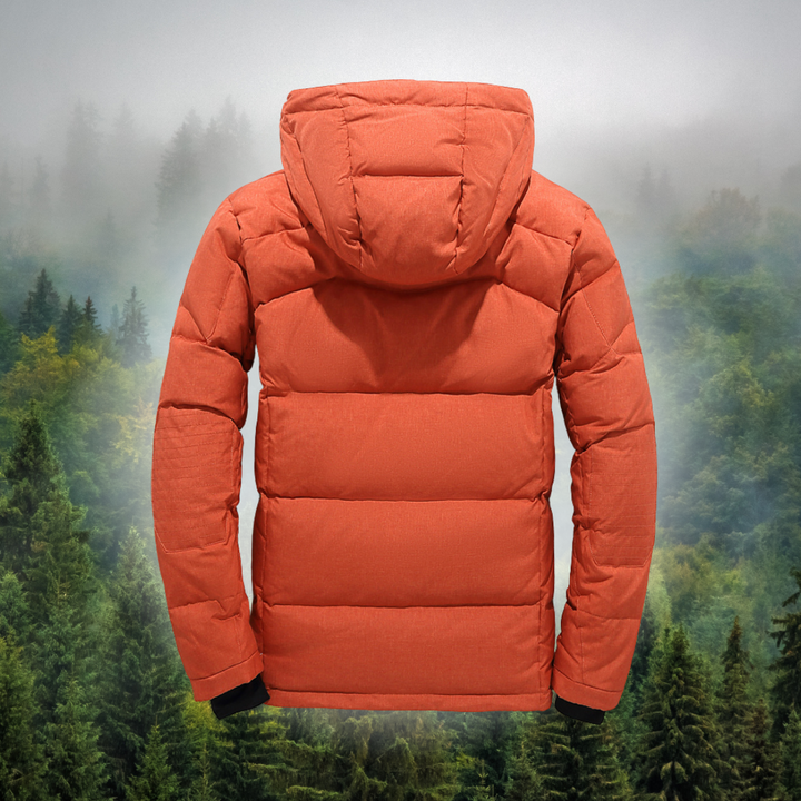 Orangefarbene Daunenjacke mit Kapuze vor nebligem Waldhintergrund. Wintermode, Outdoor-Bekleidung, warme Jacke für kaltes Wetter.