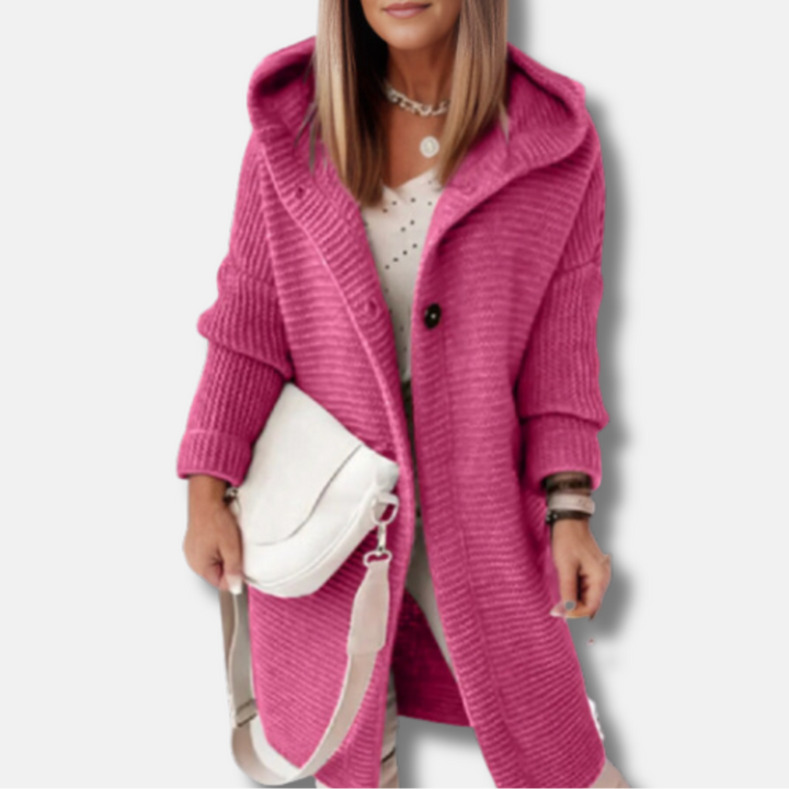 Frau in pinkem Strickmantel mit Kapuze, weißem Top und weißer Umhängetasche. Modetrend Herbst, Damenmode, stilvoller Look.