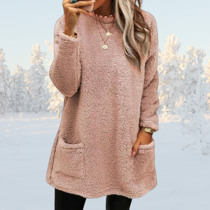 Frau in rosa Teddyfleece-Pullover mit Taschen, Winterlandschaft im Hintergrund. Modetrend, gemütlicher Look, Wintermode, Damenbekleidung.