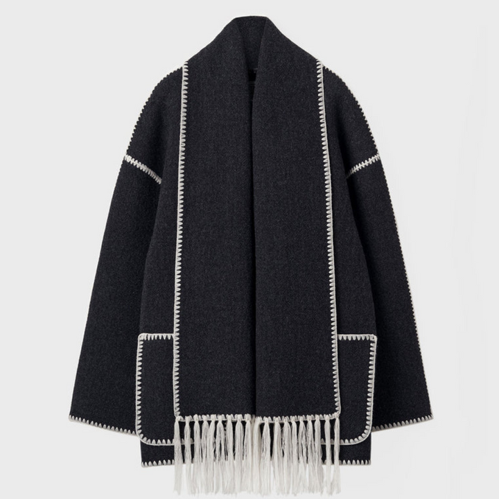 Dunkelgrauer Wollmantel mit weißen Ziernähten und Fransen, elegantes Design, modische Damenbekleidung, Herbst-Winter-Trend.