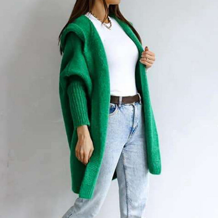 Frau in grünem Strickcardigan, weißem T-Shirt und blauer Jeans. Modetrend, lässiger Stil, Herbstmode, Damenbekleidung, Streetwear.