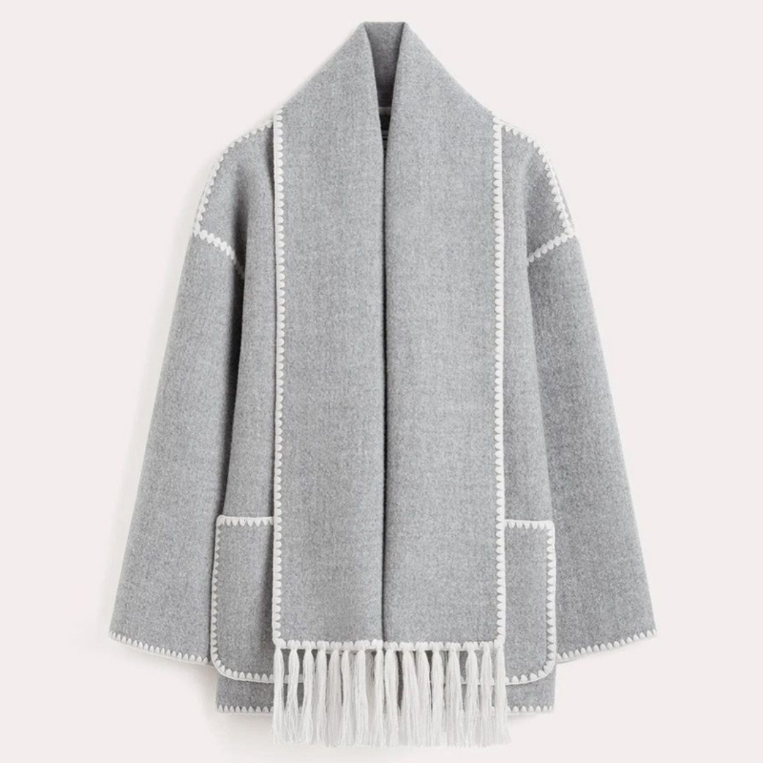 Grauer Wollmantel mit Fransen, offener Vorderseite und weißen Ziernähten. Eleganter Damenmantel, ideal für Herbstmode und Wintertrends.