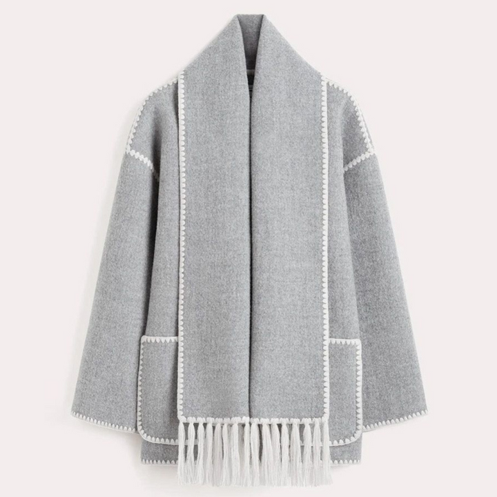 Grauer Wollmantel mit Fransen, offener Vorderseite und weißen Ziernähten. Eleganter Damenmantel, ideal für Herbstmode und Wintertrends.