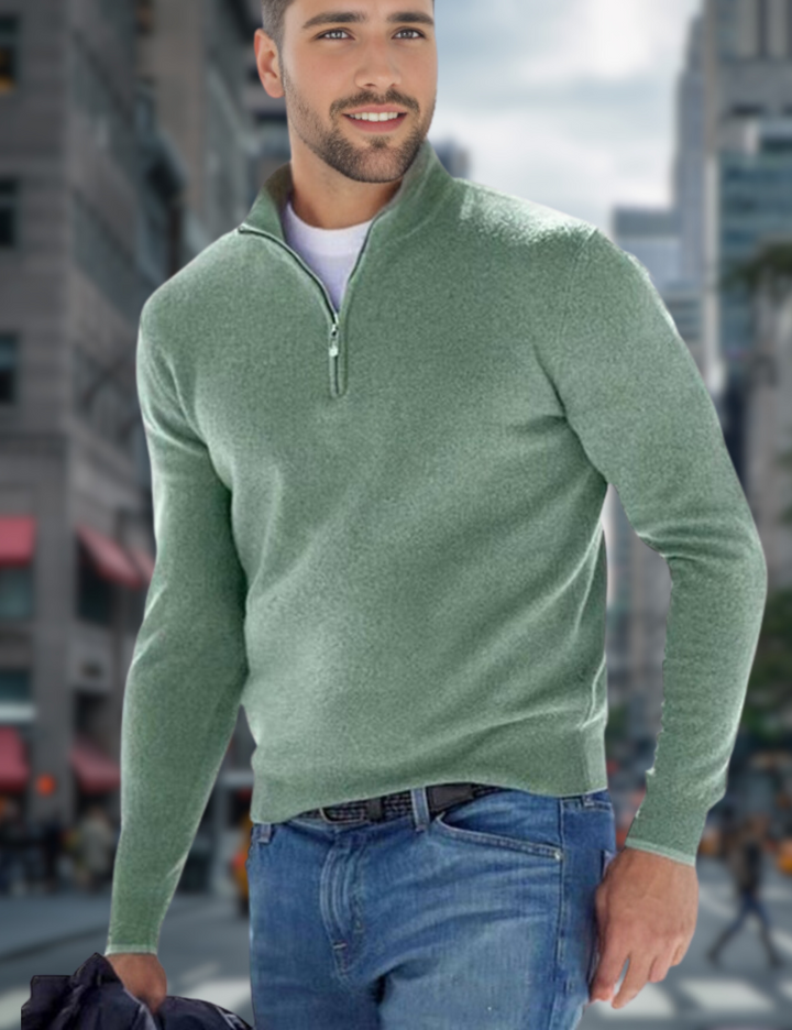Mann in grünem Pullover mit Reißverschluss und blauer Jeans spaziert durch belebte Stadtstraße. Mode, Herrenbekleidung, urbaner Stil.