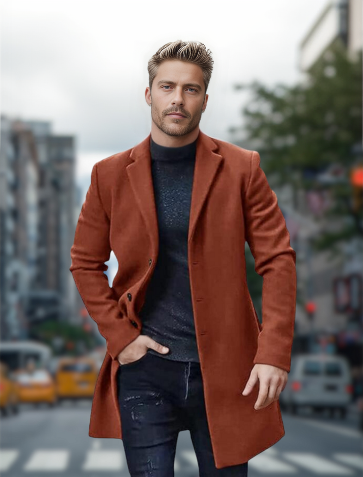 Ein Mann in einem eleganten, braunen Mantel geht selbstbewusst über eine belebte Stadtstraße. Hintergrund mit unscharfen Gebäuden und Autos.